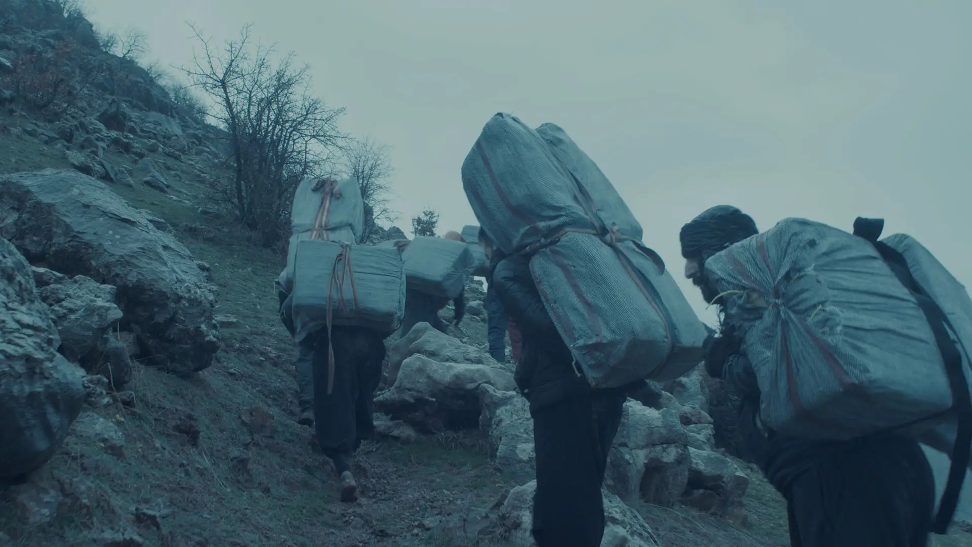 people carrying loads over a mountain.