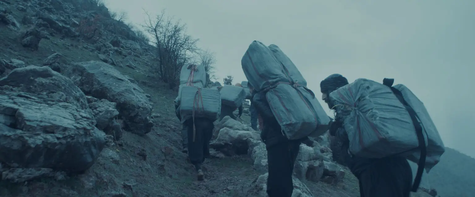 people carrying loads over a mountain.
